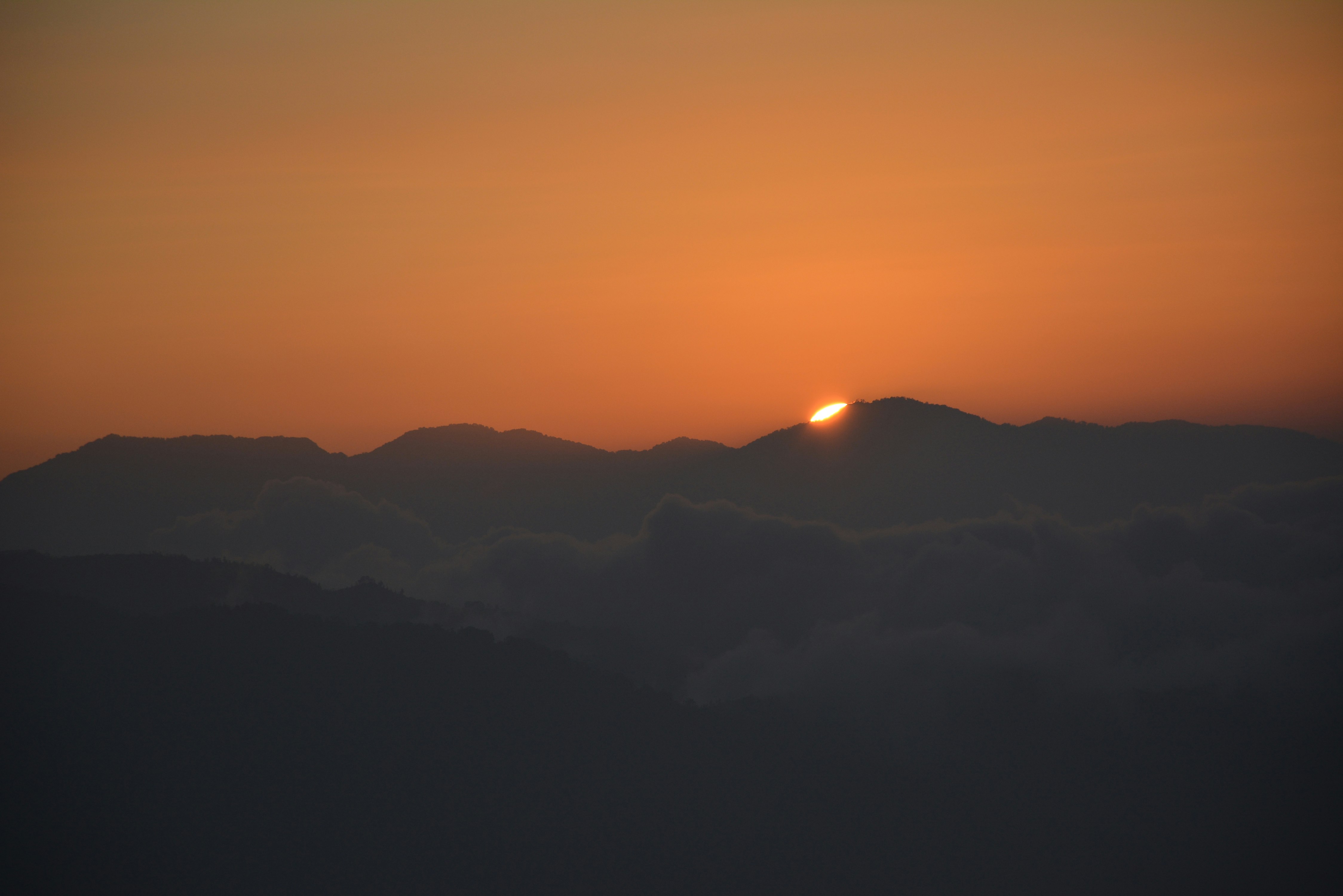 sun setting behind mountain ranges